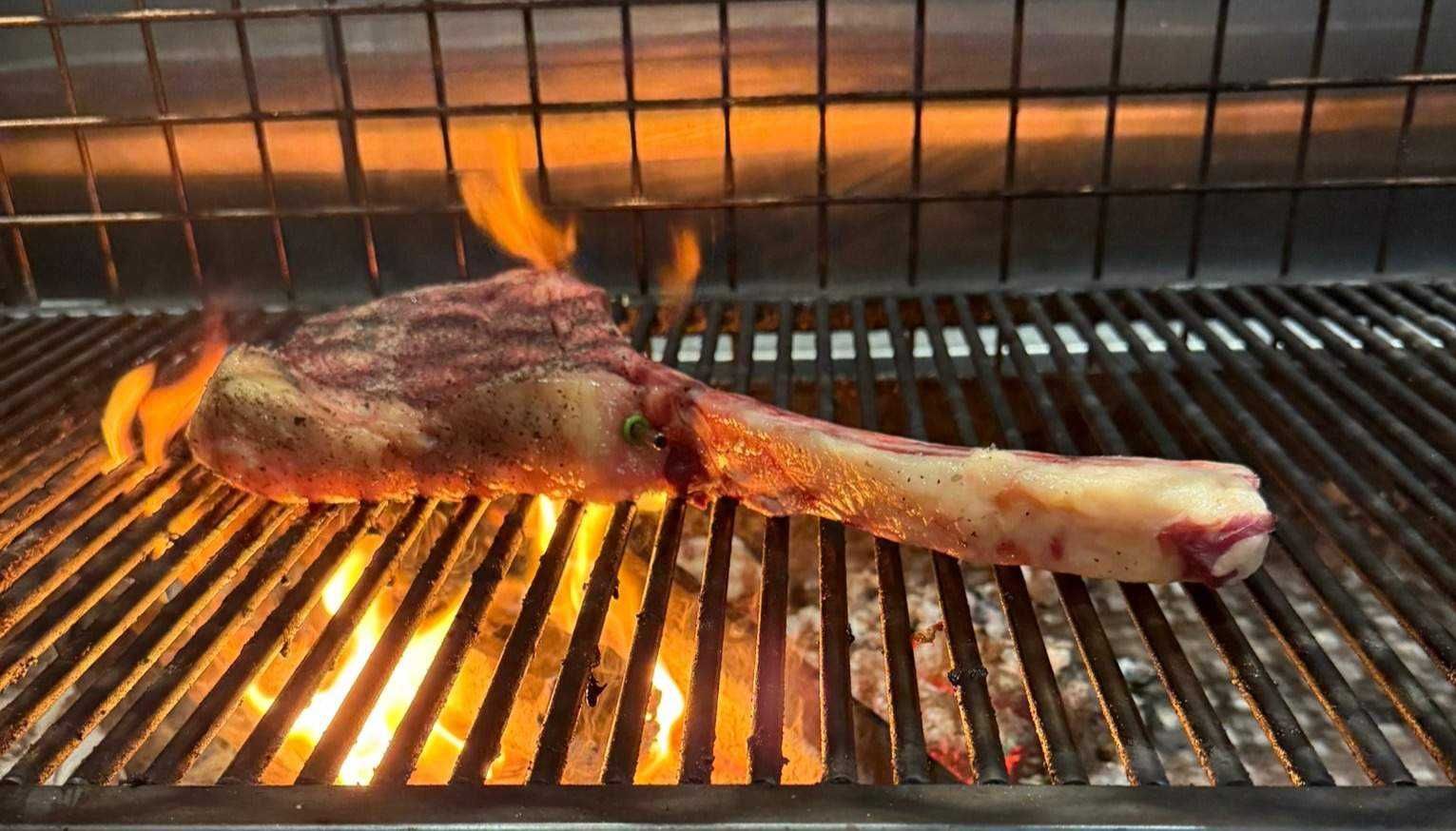 Tomahawk steak cooking over open flames at The Bach, Dundee
